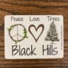 Black hills sticker with a wooden peace sign, heart, and a tree design.