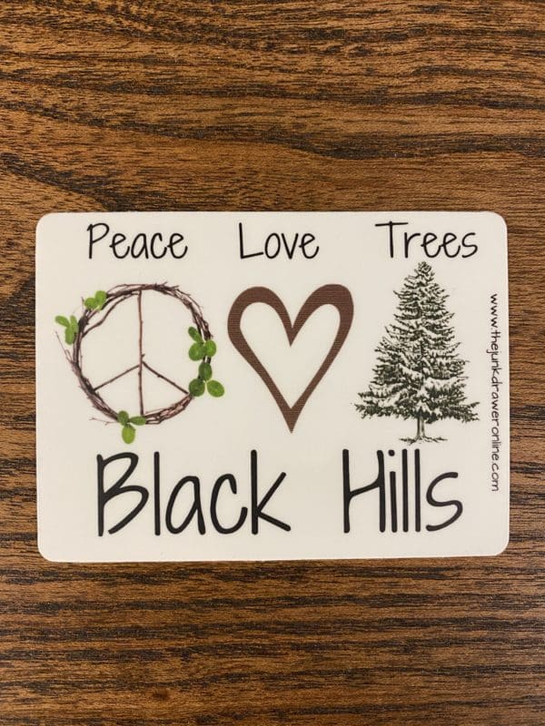 Black hills sticker with a wooden peace sign, heart, and a tree design.