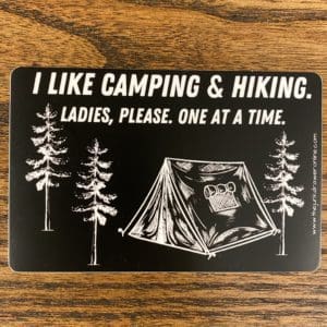 Sticker with trees and a tent and the text I like camping & Hiking. Ladies, please. One at a time.