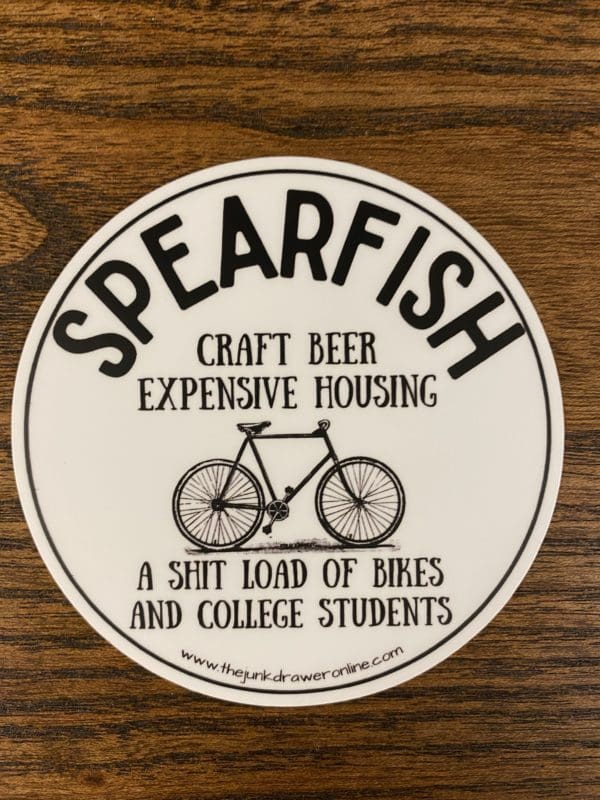 Spearfish sticker with a bicycle and the text craft beer expensive housing a shit load of bikes and college students