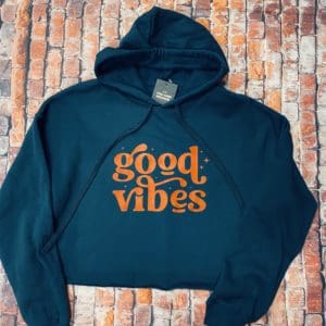View of orange good vibes text on a blue hoodie with brick background