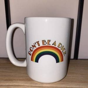 DON’T BE A DICK text with red to yellow gradient above a rainbow custom mug