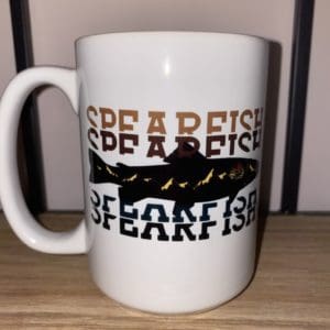 Custom mug with Spearfish text with a orange to black gradient split with a fish design with mountains and a sun within