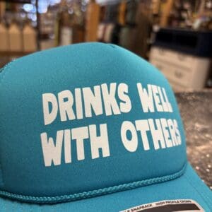 DRINKS WELL WITH OTHERS TRUCKER HAT